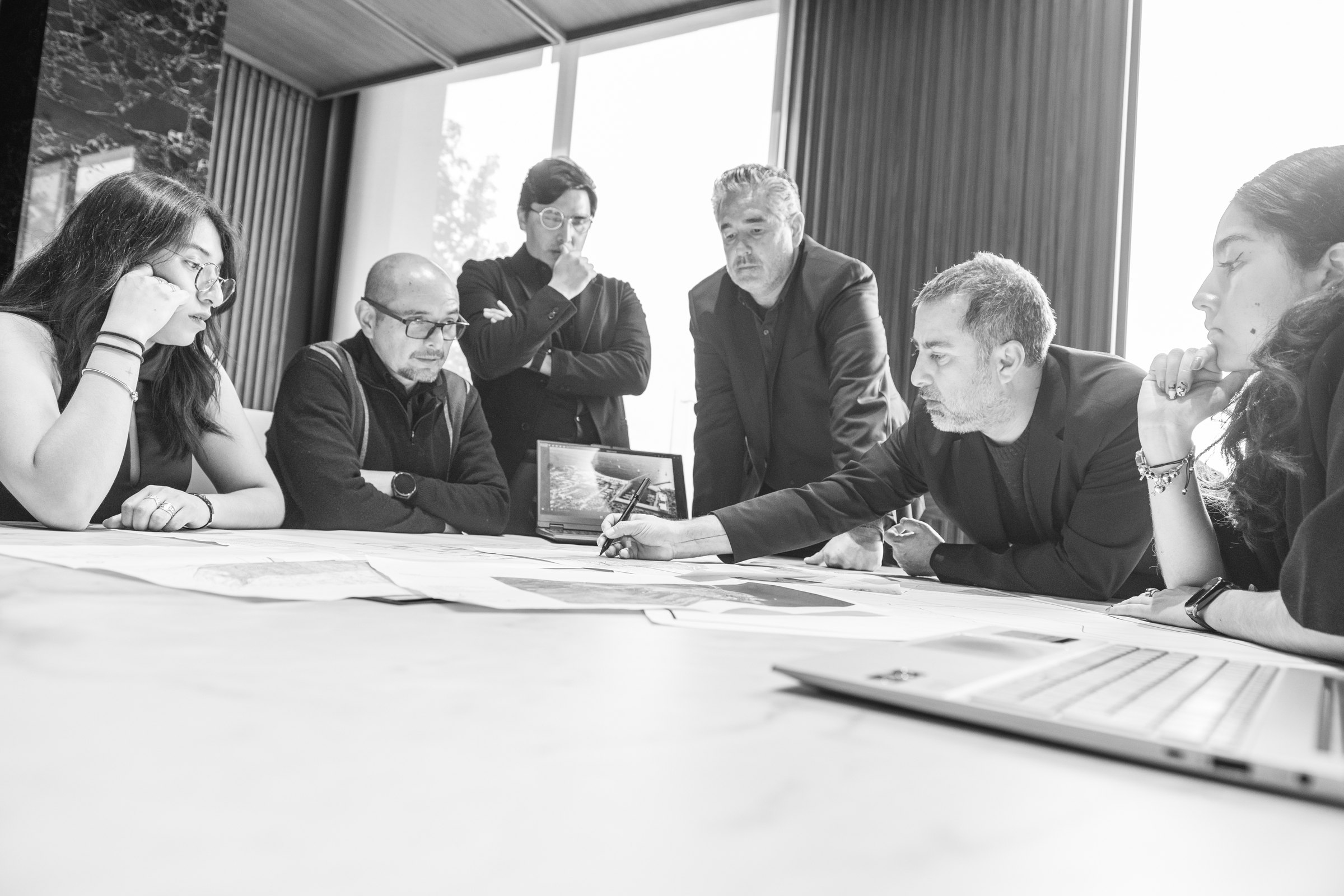 Seis integrantes del equipo de Tantum alrededor de la mesa, revisando los planos de un proyecto