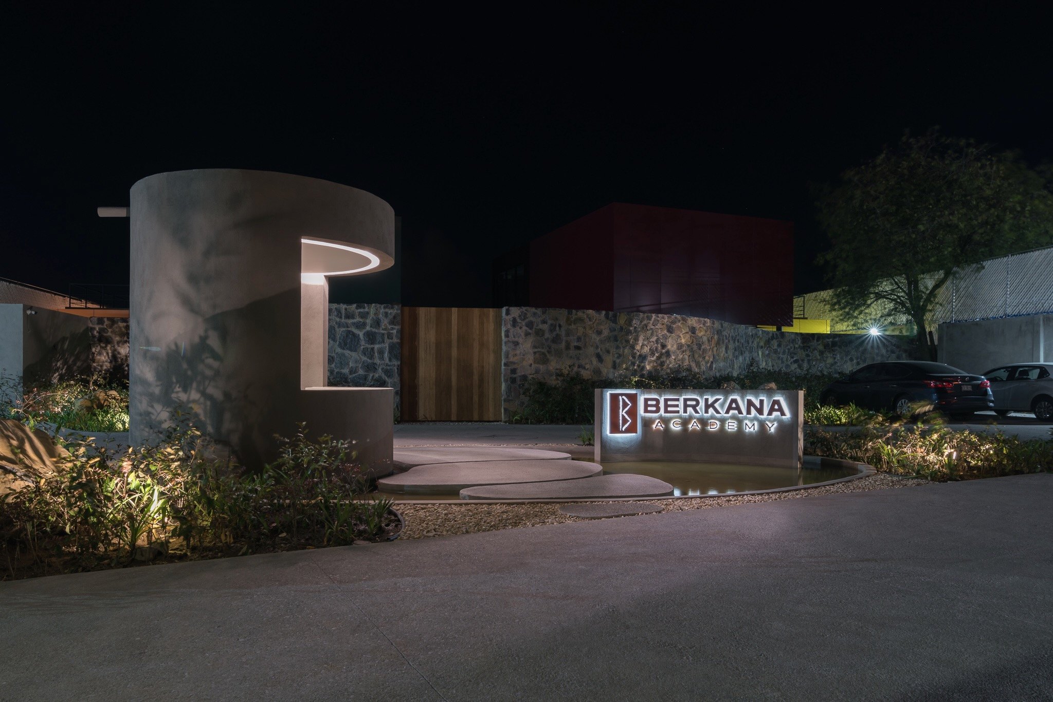 El acceso de noche, con el letrero del colegio