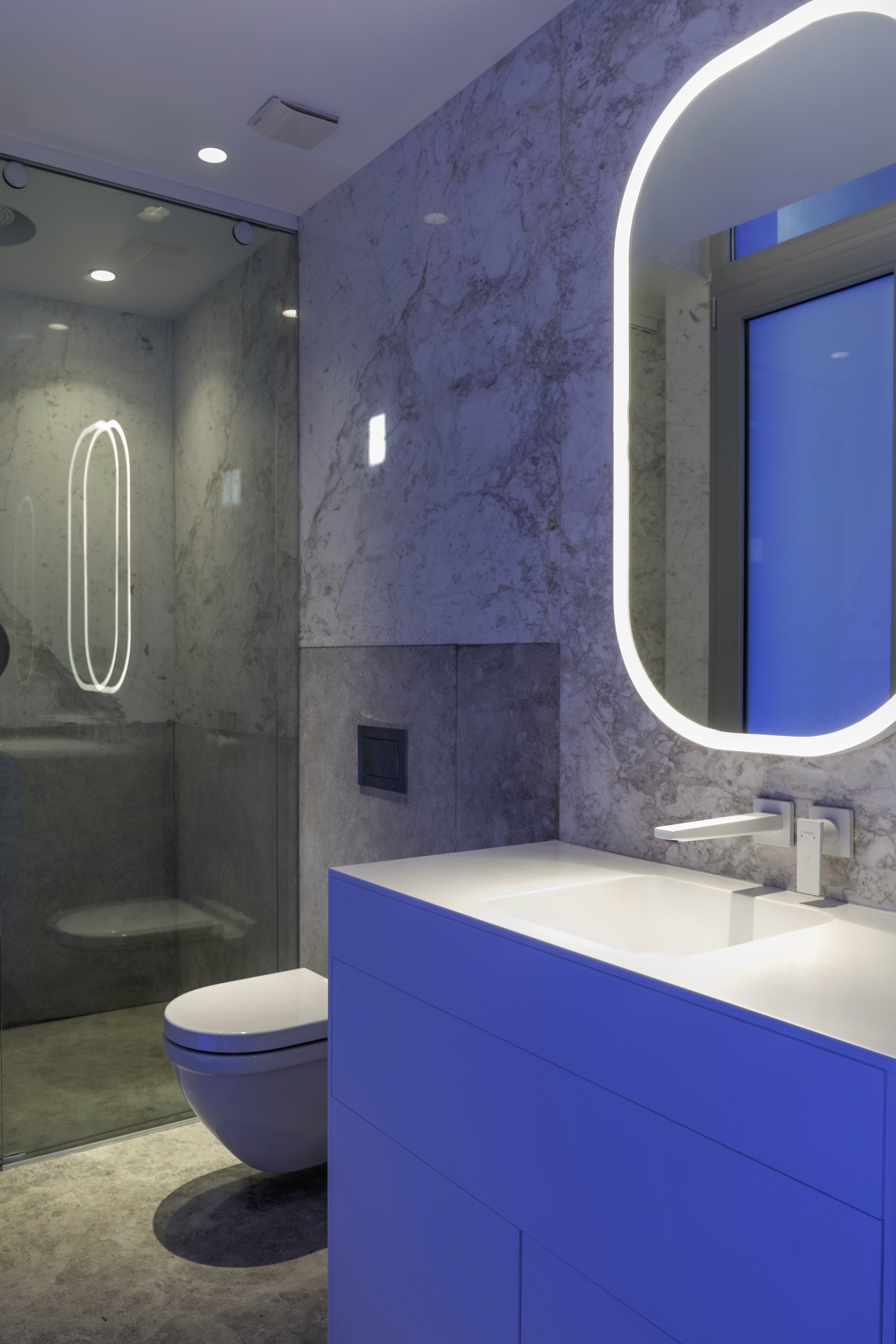 Baño con el espejo ovalado y el mueble azul
