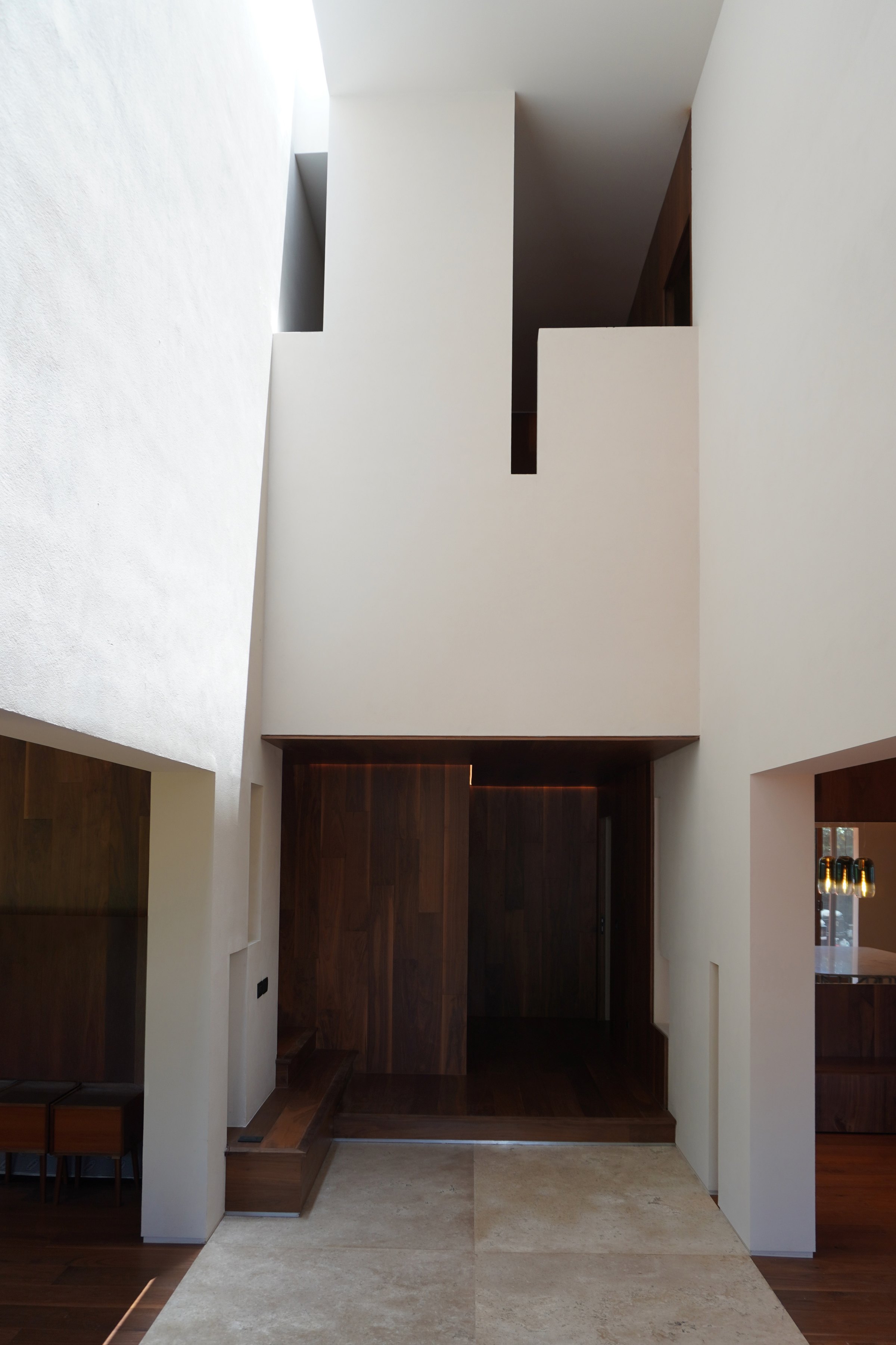 El vestíbulo de doble altura, entre el muro blanco y la madera