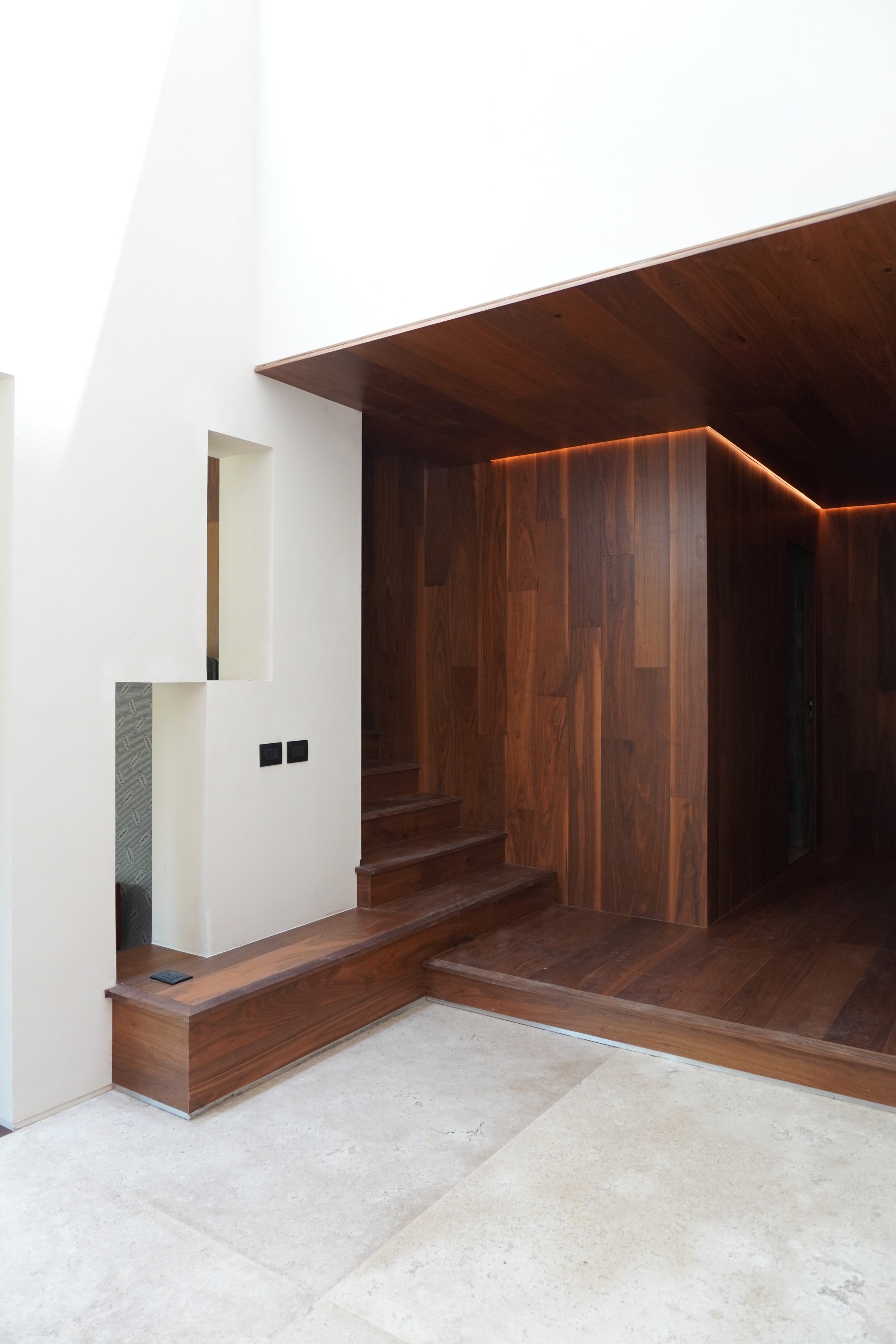 La escalera de madera arrancando junto al muro blanco
