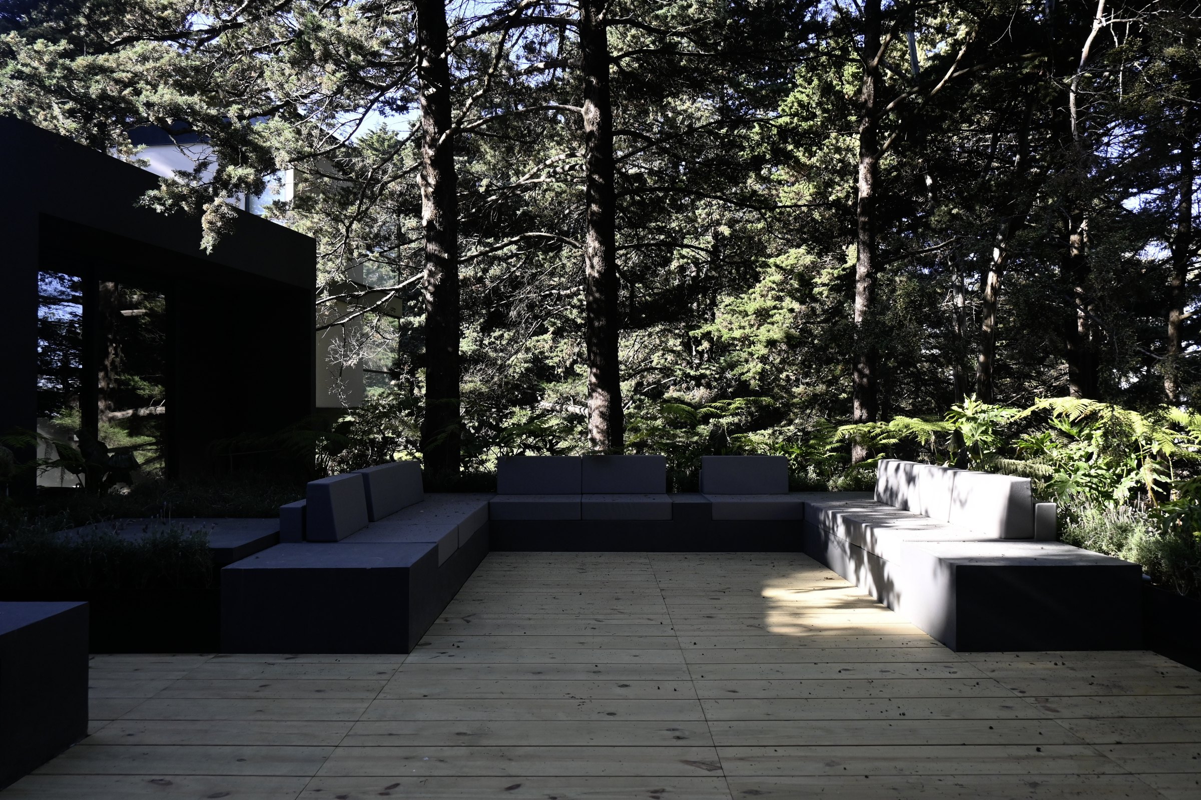 La terraza con los sillones bajos, bajo los árboles