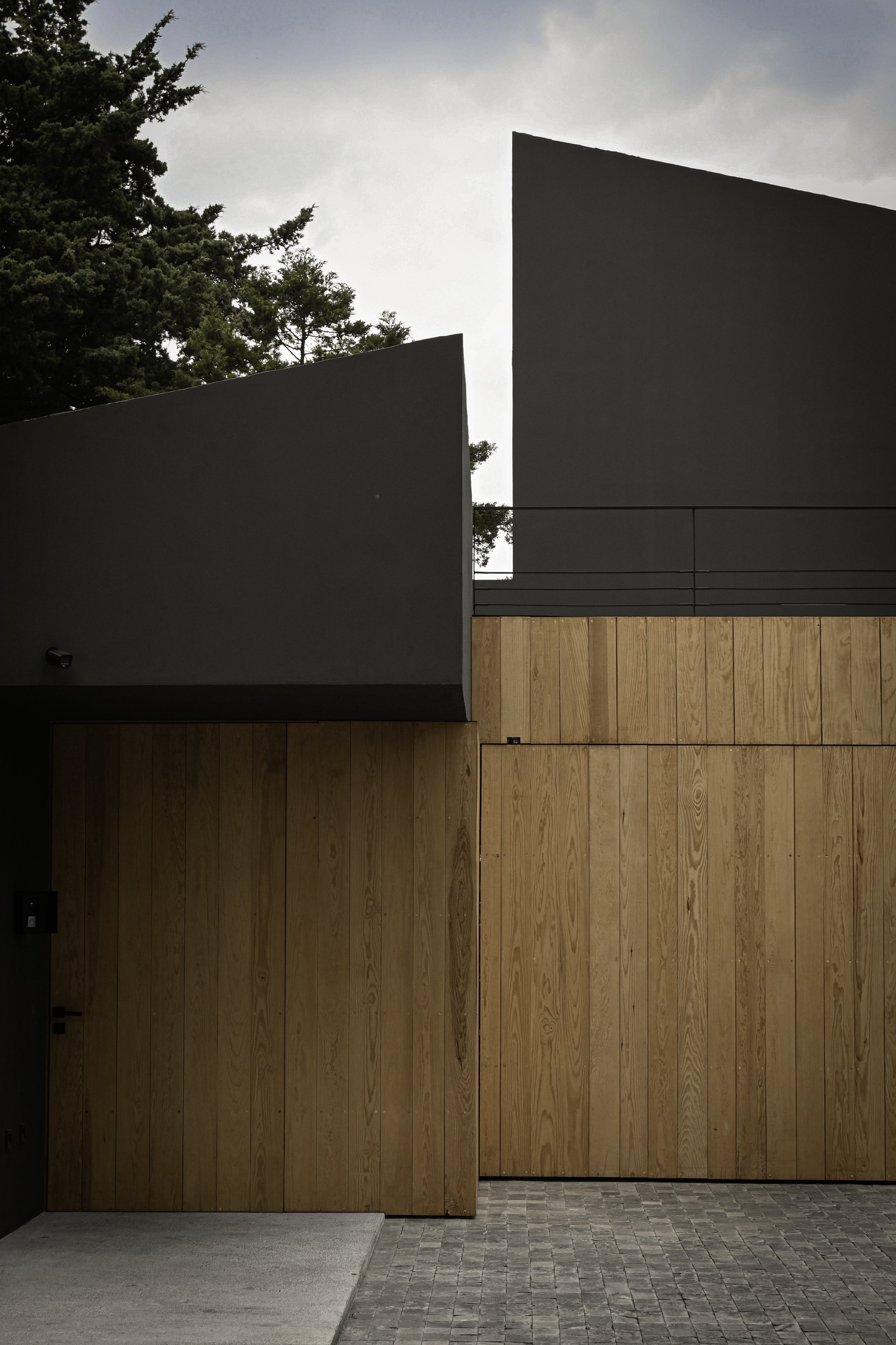 El costado de la casa, entre el muro negro y la madera