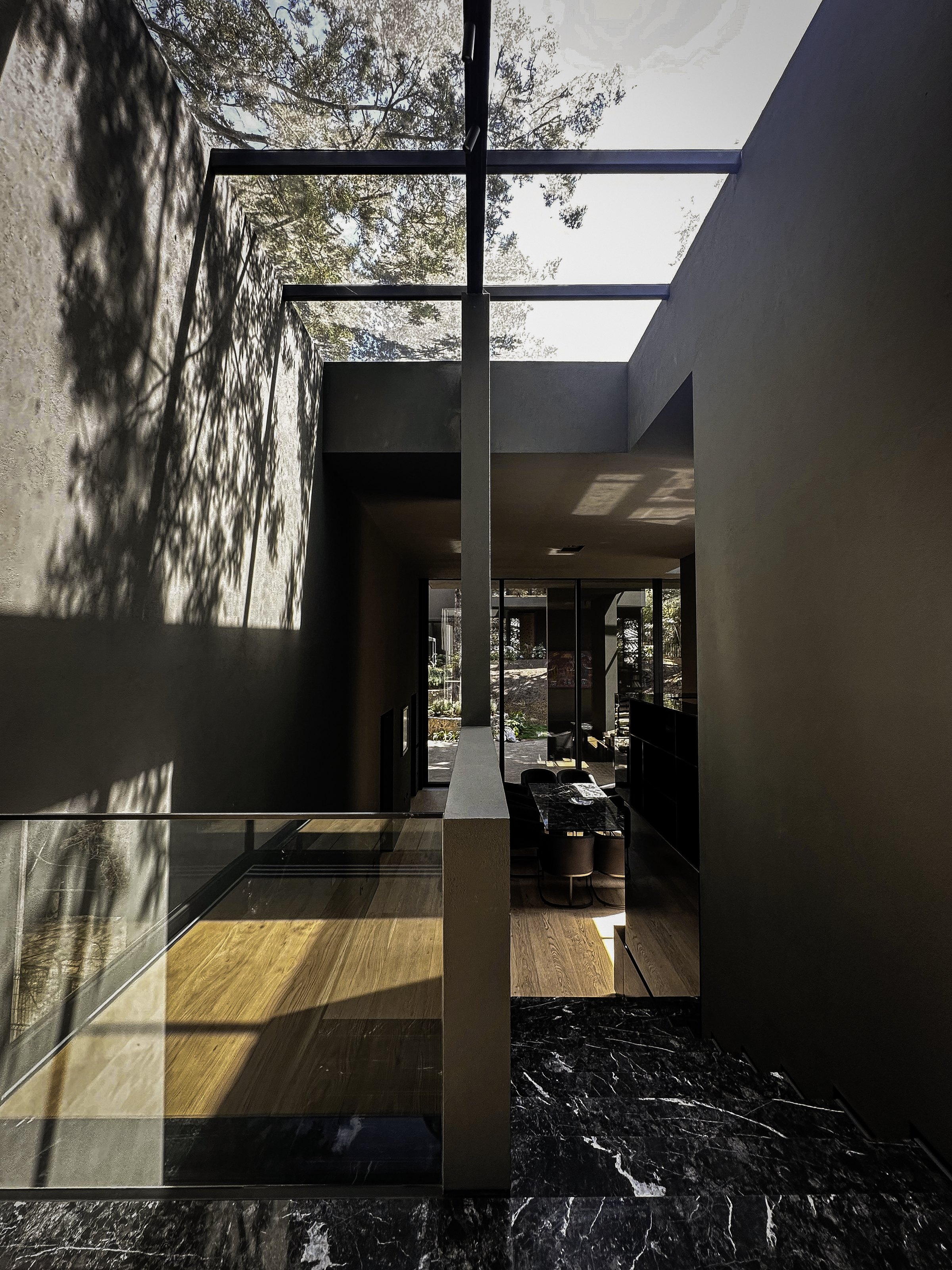 El interior visto tras el ventanal, con el bosque reflejado
