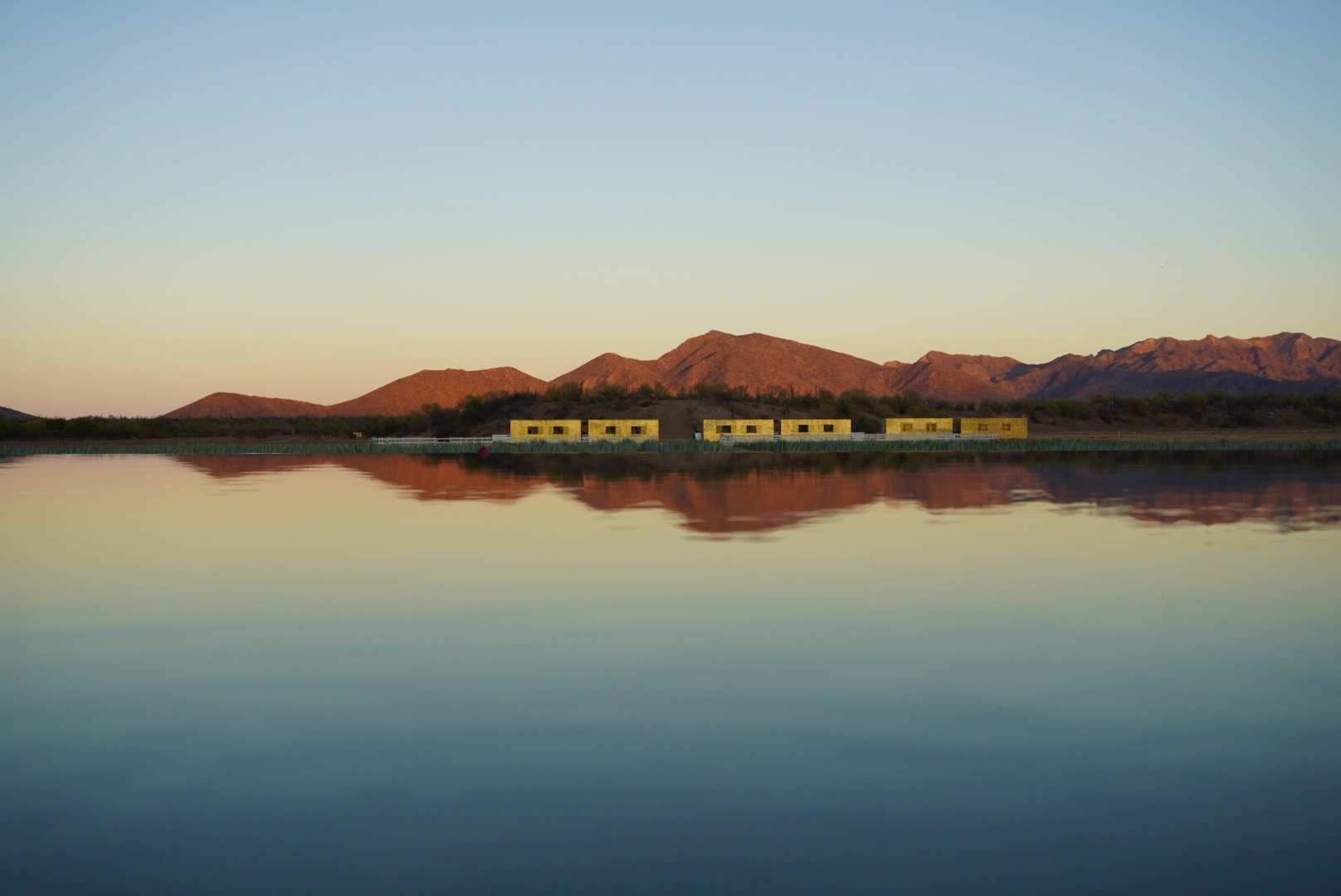 El conjunto reflejado en el agua, con la sierra al amanecer