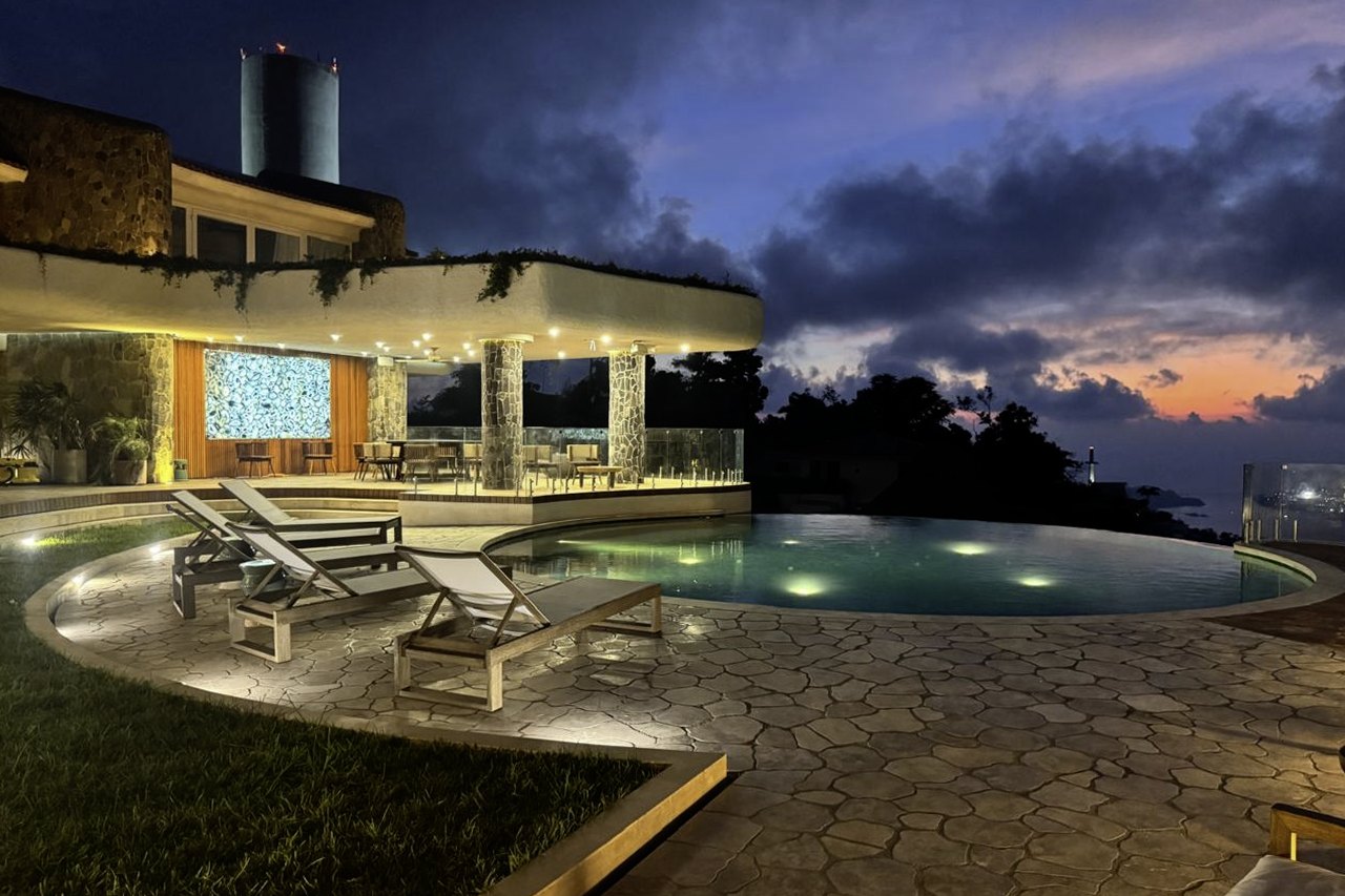La alberca y la terraza sobre la bahía al anochecer