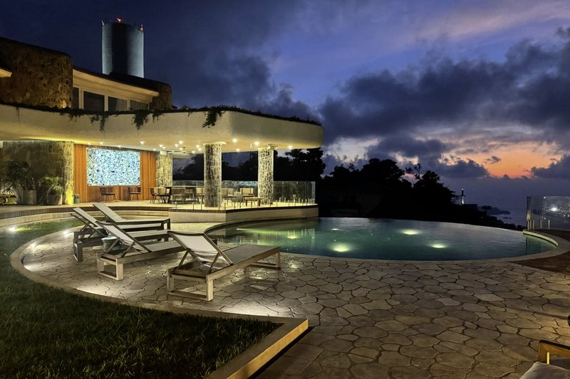La alberca y la terraza sobre la bahía al anochecer