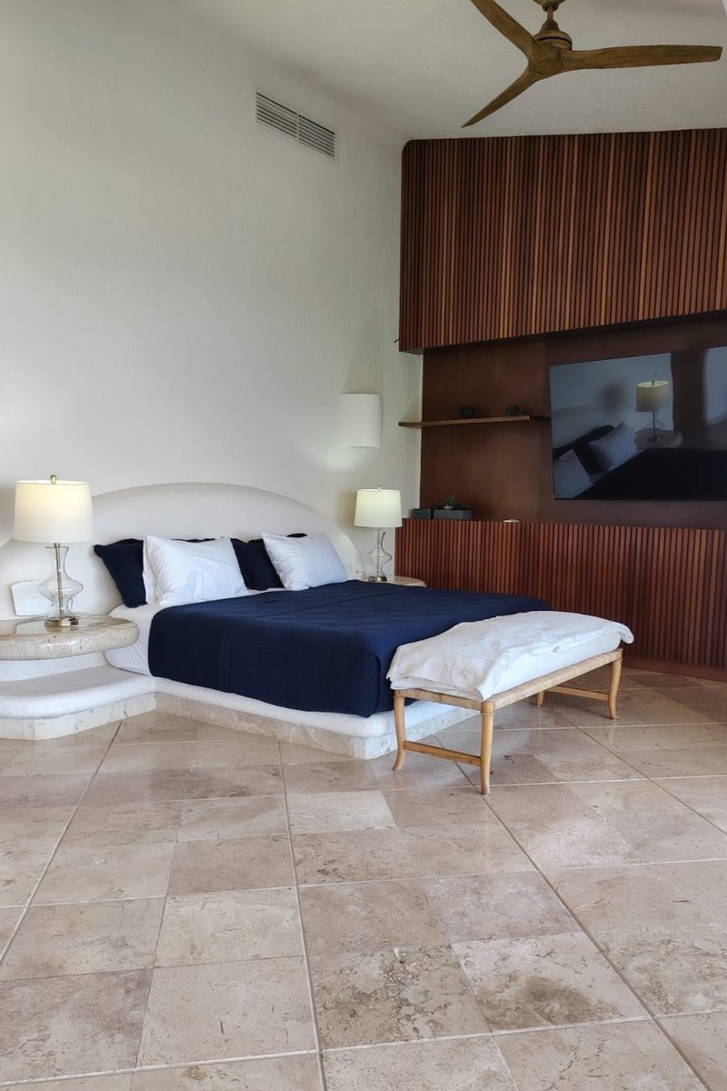 Recámara con el cabecero de madera y la cama vestida