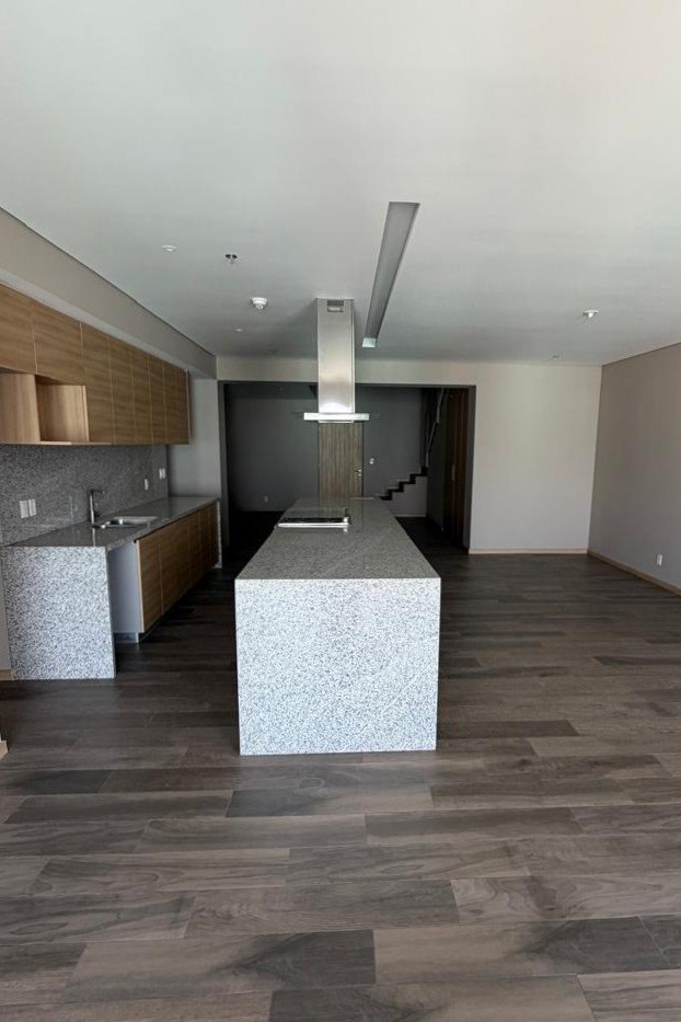 Cocina con isla de mármol y campana, sobre el piso de madera
