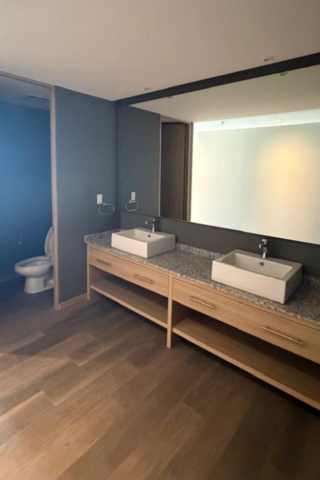 Baño con doble lavabo sobre mueble de madera y espejo corrido