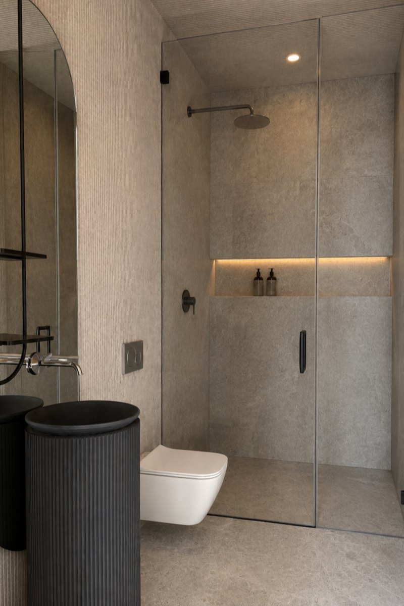 Baño con la regadera de cristal y los acabados de concreto