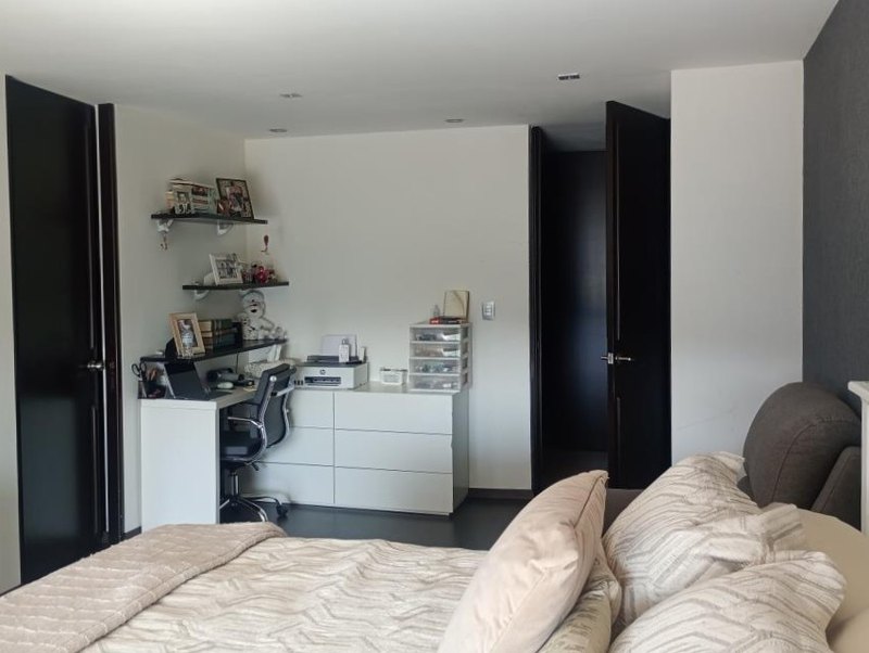 Recámara con la cama vestida y el paso al vestidor